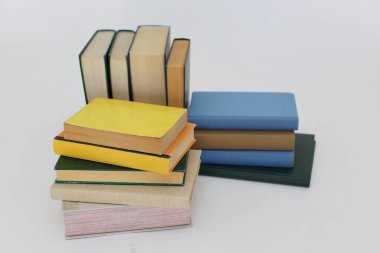 Beyaz arka plan üzerine bir yığın kitap, dünyanın en ünlü yazarlarının okumaya hazır güzel kitapları, kütüphane arkaplanının önündeki ahşap masanın üzerinde bir yığın kitap ve gözlük. eğitim ve bilgi kavramı, kütüphane, okul