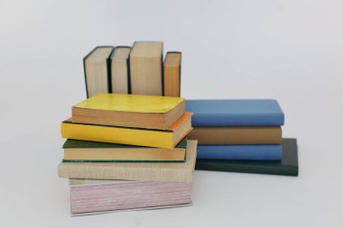 Beyaz arka plan üzerine bir yığın kitap, dünyanın en ünlü yazarlarının okumaya hazır güzel kitapları, kütüphane arkaplanının önündeki ahşap masanın üzerinde bir yığın kitap ve gözlük. eğitim ve bilgi kavramı, kütüphane, okul