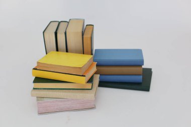 Beyaz arka plan üzerine bir yığın kitap, dünyanın en ünlü yazarlarının okumaya hazır güzel kitapları, kütüphane arkaplanının önündeki ahşap masanın üzerinde bir yığın kitap ve gözlük. eğitim ve bilgi kavramı, kütüphane, okul