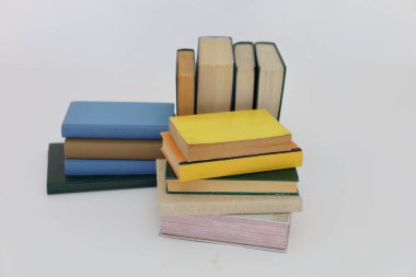 Beyaz arka plan üzerine bir yığın kitap, dünyanın en ünlü yazarlarının okumaya hazır güzel kitapları, kütüphane arkaplanının önündeki ahşap masanın üzerinde bir yığın kitap ve gözlük. eğitim ve bilgi kavramı, kütüphane, okul