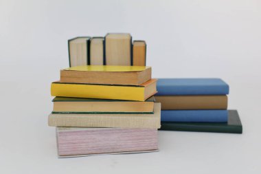 Beyaz arka plan üzerine bir yığın kitap, dünyanın en ünlü yazarlarının okumaya hazır güzel kitapları, kütüphane arkaplanının önündeki ahşap masanın üzerinde bir yığın kitap ve gözlük. eğitim ve bilgi kavramı, kütüphane, okul