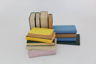 Beyaz arka plan üzerine bir yığın kitap, dünyanın en ünlü yazarlarının okumaya hazır güzel kitapları, kütüphane arkaplanının önündeki ahşap masanın üzerinde bir yığın kitap ve gözlük. eğitim ve bilgi kavramı, kütüphane, okul