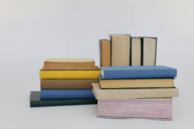 Beyaz arka plan üzerine bir yığın kitap, dünyanın en ünlü yazarlarının okumaya hazır güzel kitapları, kütüphane arkaplanının önündeki ahşap masanın üzerinde bir yığın kitap ve gözlük. eğitim ve bilgi kavramı, kütüphane, okul