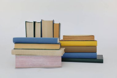 Beyaz arka plan üzerine bir yığın kitap, dünyanın en ünlü yazarlarının okumaya hazır güzel kitapları, kütüphane arkaplanının önündeki ahşap masanın üzerinde bir yığın kitap ve gözlük. eğitim ve bilgi kavramı, kütüphane, okul