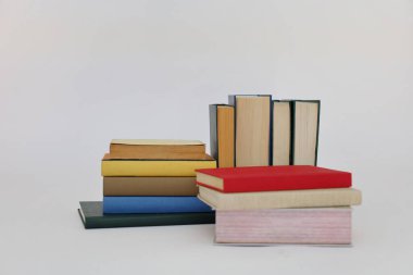 Beyaz arka plan üzerine bir yığın kitap, dünyanın en ünlü yazarlarının okumaya hazır güzel kitapları, kütüphane arkaplanının önündeki ahşap masanın üzerinde bir yığın kitap ve gözlük. eğitim ve bilgi kavramı, kütüphane, okul