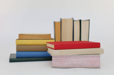 Beyaz arka plan üzerine bir yığın kitap, dünyanın en ünlü yazarlarının okumaya hazır güzel kitapları, kütüphane arkaplanının önündeki ahşap masanın üzerinde bir yığın kitap ve gözlük. eğitim ve bilgi kavramı, kütüphane, okul