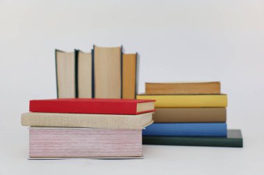 Beyaz arka plan üzerine bir yığın kitap, dünyanın en ünlü yazarlarının okumaya hazır güzel kitapları, kütüphane arkaplanının önündeki ahşap masanın üzerinde bir yığın kitap ve gözlük. eğitim ve bilgi kavramı, kütüphane, okul