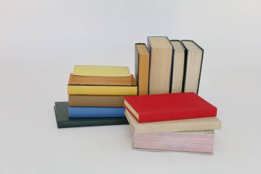 Beyaz arka plan üzerine bir yığın kitap, dünyanın en ünlü yazarlarının okumaya hazır güzel kitapları, kütüphane arkaplanının önündeki ahşap masanın üzerinde bir yığın kitap ve gözlük. eğitim ve bilgi kavramı, kütüphane, okul