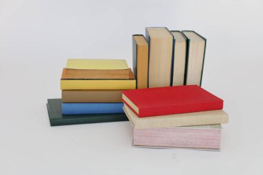 Beyaz arka plan üzerine bir yığın kitap, dünyanın en ünlü yazarlarının okumaya hazır güzel kitapları, kütüphane arkaplanının önündeki ahşap masanın üzerinde bir yığın kitap ve gözlük. eğitim ve bilgi kavramı, kütüphane, okul