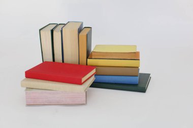 Beyaz arka plan üzerine bir yığın kitap, dünyanın en ünlü yazarlarının okumaya hazır güzel kitapları, kütüphane arkaplanının önündeki ahşap masanın üzerinde bir yığın kitap ve gözlük. eğitim ve bilgi kavramı, kütüphane, okul