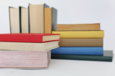 Beyaz arka plan üzerine bir yığın kitap, dünyanın en ünlü yazarlarının okumaya hazır güzel kitapları, kütüphane arkaplanının önündeki ahşap masanın üzerinde bir yığın kitap ve gözlük. eğitim ve bilgi kavramı, kütüphane, okul