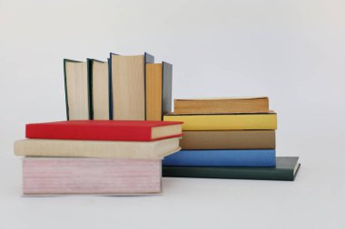 Beyaz arka plan üzerine bir yığın kitap, dünyanın en ünlü yazarlarının okumaya hazır güzel kitapları, kütüphane arkaplanının önündeki ahşap masanın üzerinde bir yığın kitap ve gözlük. eğitim ve bilgi kavramı, kütüphane, okul