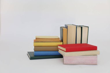 Beyaz arka plan üzerine bir yığın kitap, dünyanın en ünlü yazarlarının okumaya hazır güzel kitapları, kütüphane arkaplanının önündeki ahşap masanın üzerinde bir yığın kitap ve gözlük. eğitim ve bilgi kavramı, kütüphane, okul