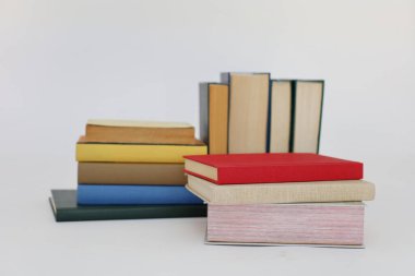 Beyaz arka plan üzerine bir yığın kitap, dünyanın en ünlü yazarlarının okumaya hazır güzel kitapları, kütüphane arkaplanının önündeki ahşap masanın üzerinde bir yığın kitap ve gözlük. eğitim ve bilgi kavramı, kütüphane, okul