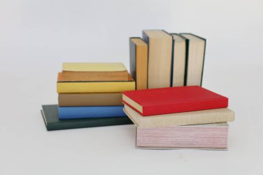 Beyaz arka plan üzerine bir yığın kitap, dünyanın en ünlü yazarlarının okumaya hazır güzel kitapları, kütüphane arkaplanının önündeki ahşap masanın üzerinde bir yığın kitap ve gözlük. eğitim ve bilgi kavramı, kütüphane, okul