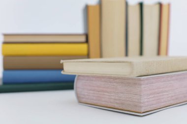 Beyaz arka plan üzerine bir yığın kitap, dünyanın en ünlü yazarlarının okumaya hazır güzel kitapları, kütüphane arkaplanının önündeki ahşap masanın üzerinde bir yığın kitap ve gözlük. eğitim ve bilgi kavramı, kütüphane, okul