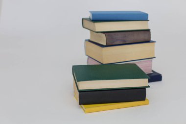 Beyaz arka planda renkli ve beyaz kitapların olduğu bir yığın kitap..