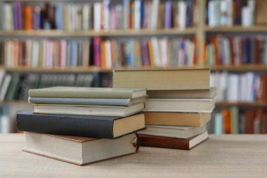 Kütüphanedeki ahşap masada yığınla kitap.
