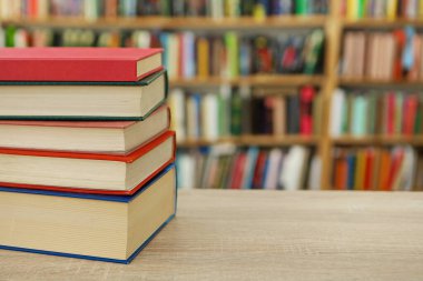 Kütüphanedeki ahşap masada yığınla kitap.