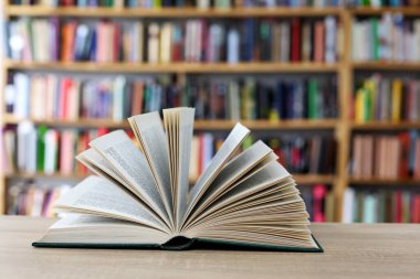 Kütüphanedeki ahşap masanın üzerinde bir yığın kitap.