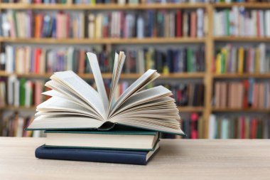 stack of books in library on wooden table, space for text