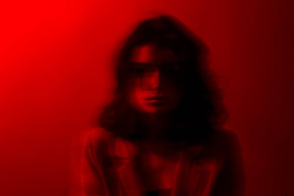 Portrait of woman with makeup and hairstyle, wear red suit, with closed eyes, red studio light and effects.