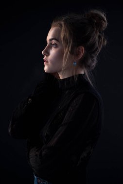 Profile portrait of a young female model, wear black suitcase, isolated black background.