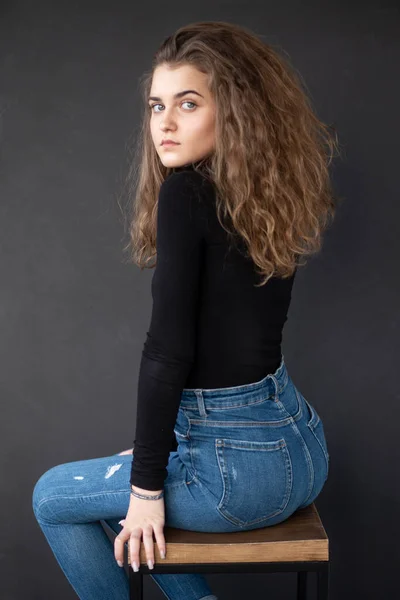 Sensual Girl Curly Hair Sitting High Chair Grey Background Looking Stockafbeelding