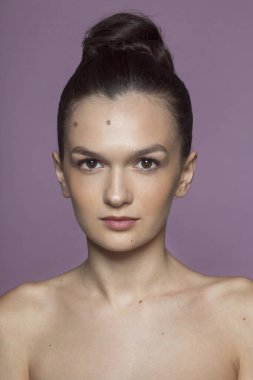 Ön planda güzel esmer bir kadın var. Makyajlı, dar saçlı, izole bir menekşe arka planı var..