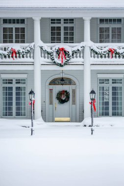 Altın ve beyaz ön kapı Noel süslemeleri ve kar ile süslenmiş, dikey