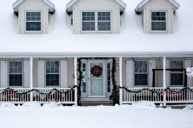 Front door of house decorated with Christmas decorations and snow, horizontal