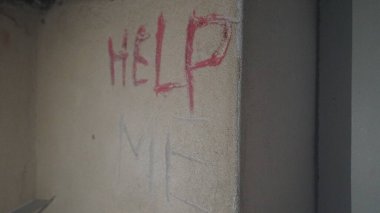 Karanlıkta eski bir binanın içindeki duvara yazılmış yardım edin.