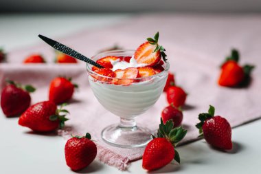 Bir el tarafından kaldırılan Yunan yoğurdu ve çilekleri taze ve lezzetli süt bazlı besinleri sembolize ediyor.