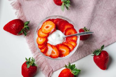 Lezzetli bir tatlı bardağında taze çilek ve yoğun Yunan yoğurdu, bir kaşık da tadını çıkarmaya hazır. Temiz yemek konsepti..