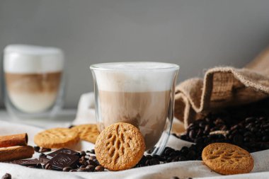 Gri arka planda kurabiyeli bir bardak süt ve kahve.