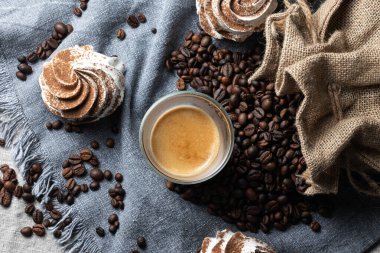 Kahve fincanı, kahve çekirdeği ve siyah arka planda kurabiyeler.