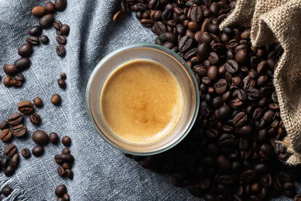 Bir fincan kahve, kahve çekirdeği ve ahşap bir arka plan..