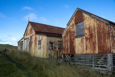 Çiftliği olan terk edilmiş eski bir ev. İzlanda deniz kıyısına yakın bir alan. Açık çimenler. Beyaz bulutlu mavi gökyüzü. Holmsvollur, Sudurnesjabaer, İzlanda.