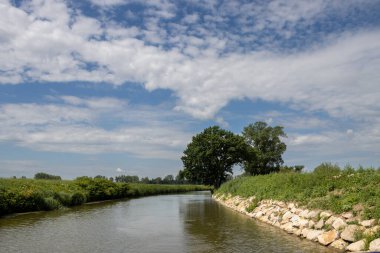 Bata 'nın Morava bölgesi ile Slovakya arasında inşa ettiği kanal. Güzergahı çevreleyen güzel yeşillikler, ağaçlar, çalılar, çimenler ve çiçekler. Beyaz bulutlu mavi gökyüzü. Bata Kanalı, Çek ve Slovakya Cumhuriyeti