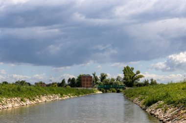 Bata 'nın Morava bölgesi ile Slovakya arasında inşa ettiği kanal. Güzergahı çevreleyen güzel yeşillikler, ağaçlar, çalılar, çimenler ve çiçekler. Beyaz bulutlu mavi gökyüzü. Bata Kanalı, Çek ve Slovakya Cumhuriyeti