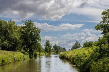 Bata 'nın Morava bölgesi ile Slovakya arasında inşa ettiği kanal. Güzergahı çevreleyen güzel yeşillikler, ağaçlar, çalılar, çimenler ve çiçekler. Beyaz bulutlu mavi gökyüzü. Bata Kanalı, Çek ve Slovakya Cumhuriyeti