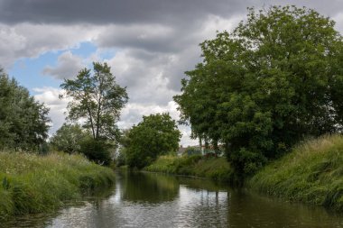 Bata 'nın Morava bölgesi ile Slovakya arasında inşa ettiği kanal. Güzergahı çevreleyen güzel yeşillikler, ağaçlar, çalılar, çimenler ve çiçekler. Beyaz bulutlu mavi gökyüzü. Bata Kanalı, Çek ve Slovakya Cumhuriyeti