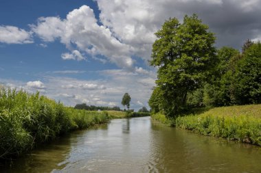 Bata 'nın Morava bölgesi ile Slovakya arasında inşa ettiği kanal. Güzergahı çevreleyen güzel yeşillikler, ağaçlar, çalılar, çimenler ve çiçekler. Beyaz bulutlu mavi gökyüzü. Bata Kanalı, Çek ve Slovakya Cumhuriyeti