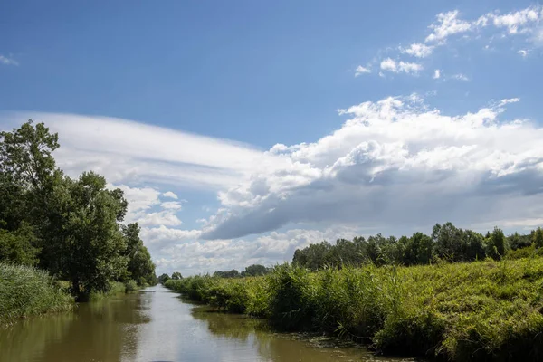 Bata 'nın Morava bölgesi ile Slovakya arasında inşa ettiği kanal. Güzergahı çevreleyen güzel yeşillikler, ağaçlar, çalılar, çimenler ve çiçekler. Beyaz bulutlu mavi gökyüzü. Bata Kanalı, Çek ve Slovakya Cumhuriyeti