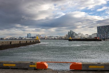 Limandaki Kuzey Atlantik Okyanusu kıyısında. Yoğun bulutlu gökyüzü olan şehir manzarası. Şiddetli rüzgarlı bir gün dalgalar yarattı. Reykjavik Limanı, İzlanda.