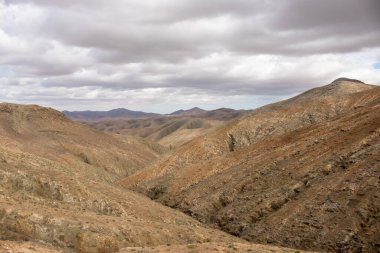 Shapes and lines of the mountains of the volcanic origin. Light brown color of the soil. Sky with clouds in the winter. Mirador Astronomico (Astronimical Viewpoint), Fuerteventura, Canary Islands