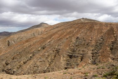 Shapes and lines of the mountains of the volcanic origin. Light brown color of the soil. Sky with clouds in the winter. Mirador Astronomico (Astronimical Viewpoint), Fuerteventura, Canary Islands