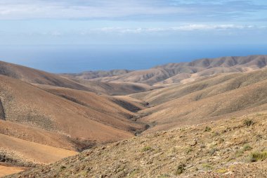 Shapes and lines of the mountains of the volcanic origin. Light brown color of the soil. Sky with clouds in the winter. Mirador Astronomico (Astronimical Viewpoint), Fuerteventura, Canary Islands