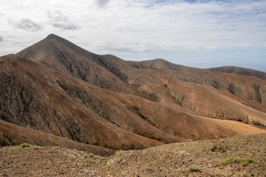 Shapes and lines of the mountains of the volcanic origin. Light brown color of the soil. Sky with clouds in the winter. Mirador Astronomico (Astronimical Viewpoint), Fuerteventura, Canary Islands