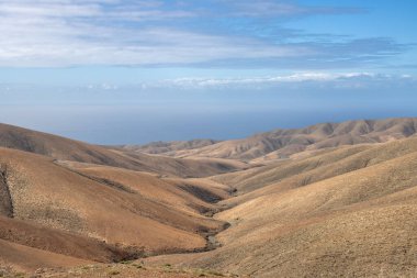 Shapes and lines of the mountains of the volcanic origin. Light brown color of the soil. Sky with clouds in the winter. Mirador Astronomico (Astronimical Viewpoint), Fuerteventura, Canary Islands